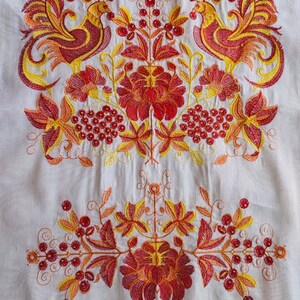 May include: White fabric with embroidered red, yellow, and orange floral design. The design features two stylized birds with long tails and a central floral motif.