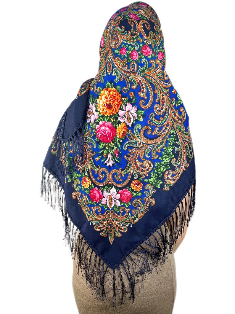 Peut inclure: Un foulard bleu &agrave; motifs paisley avec des motifs floraux et des franges noires.