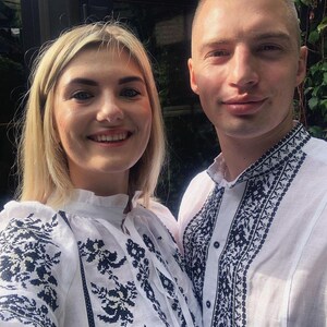 Puede incluir: Un selfie de dos personas que visten camisas blancas con intrincados bordados negros. Las camisas presentan detallados dise&ntilde;os florales y geom&eacute;tricos alrededor del cuello, las mangas y el pecho. La mujer tiene el pelo rubio y el hombre tiene el pelo corto.