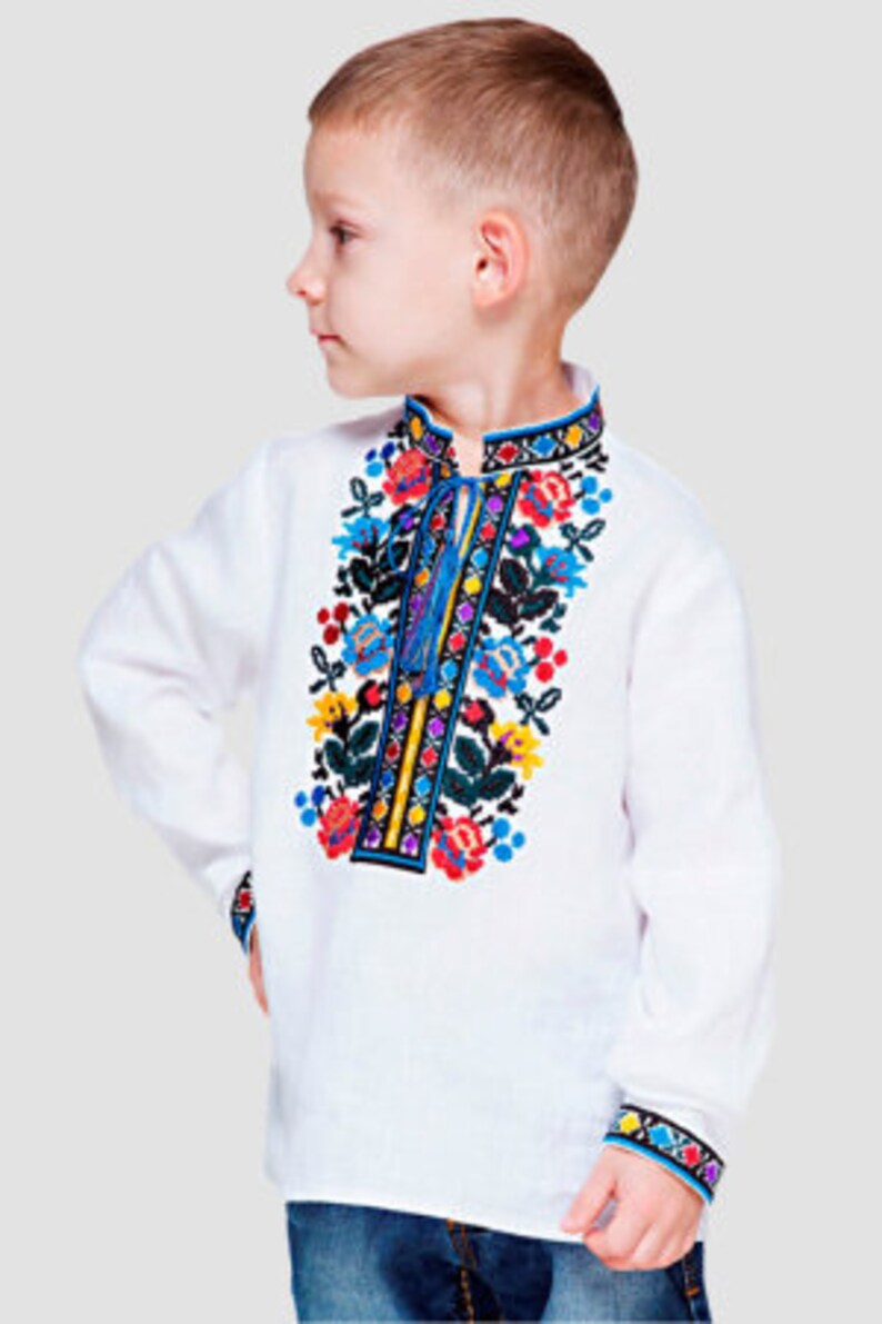 May include: A white linen shirt with colorful embroidered flowers and a blue trim. The shirt has a stand-up collar and long sleeves.