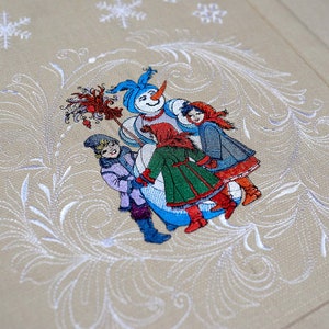 Op de afbeelding: Geborduurde wintersc&egrave;ne met een sneeuwpop en kinderen. De sneeuwpop heeft een blauwe hoed en een wortelneus. De kinderen dragen jassen in rood, groen en blauw. De achtergrond is beige met witte sneeuwvlokken en wervelpatronen.