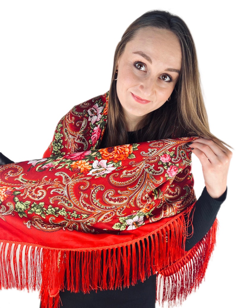 May include: A red shawl with a floral pattern and fringe. The shawl is made of a soft, lightweight fabric and is perfect for adding a touch of elegance to any outfit.