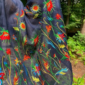 Puede incluir: Una bufanda negra de gasa con bordado floral de colores. El bordado presenta flores rojas, amarillas, verdes y azules.