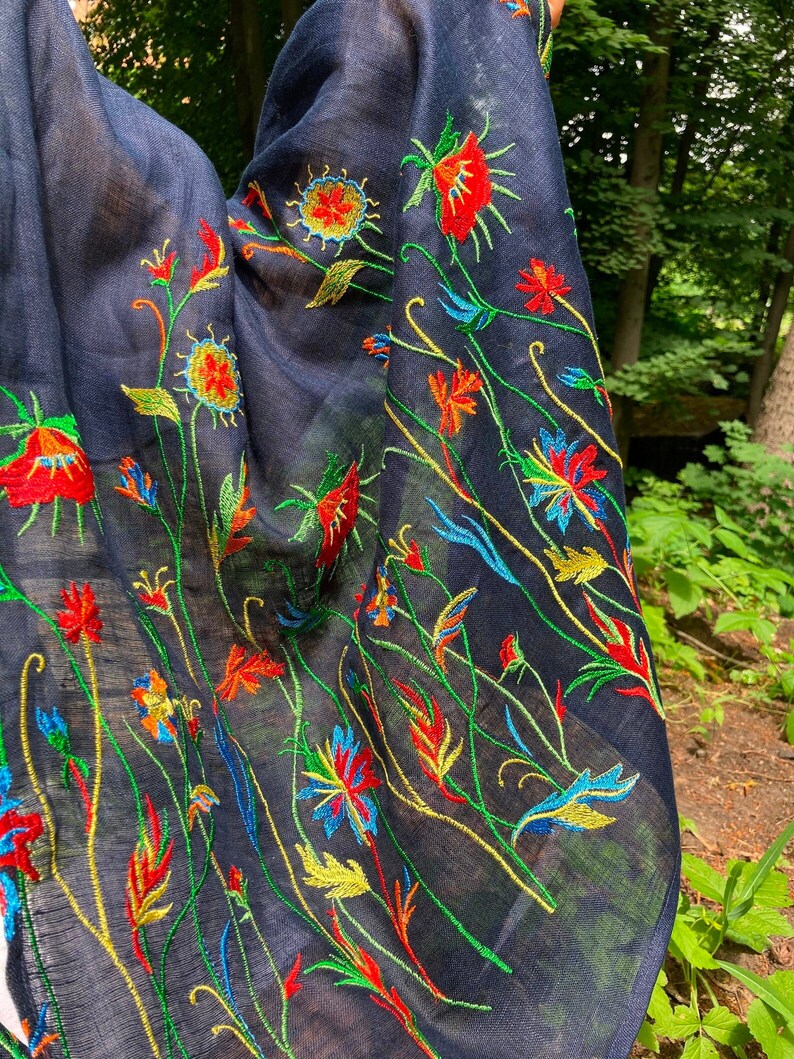 Puede incluir: Una bufanda negra de gasa con bordado floral de colores. El bordado presenta flores rojas, amarillas, verdes y azules.
