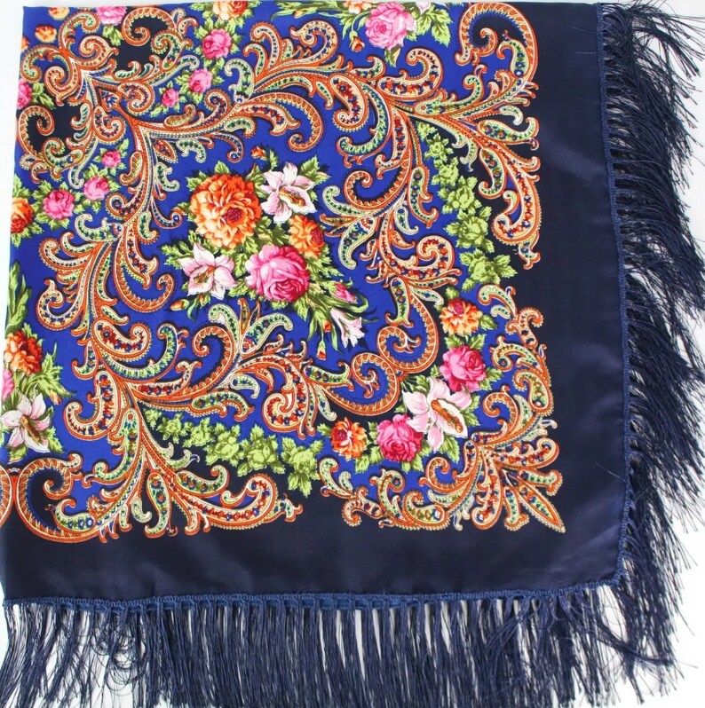 Pu&ograve; includere: Una sciarpa blu con motivo paisley e design floreale con frange.