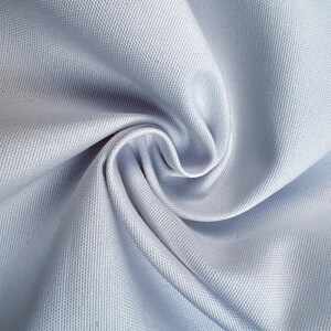 K&ouml;nnte beinhalten: Nahaufnahme eines hellblauen Stoffes mit feiner Textur. Der Stoff ist dicht gewebt, mit sichtbaren diagonalen Linien. Das Material ist gefaltet und gewirbelt, wodurch ein Spiraleffekt in der Mitte entsteht. Das Gesamtbild ist glatt und weich.