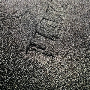 May include: Close-up of a black textured surface with the word "REMARKABLE" embossed in white.