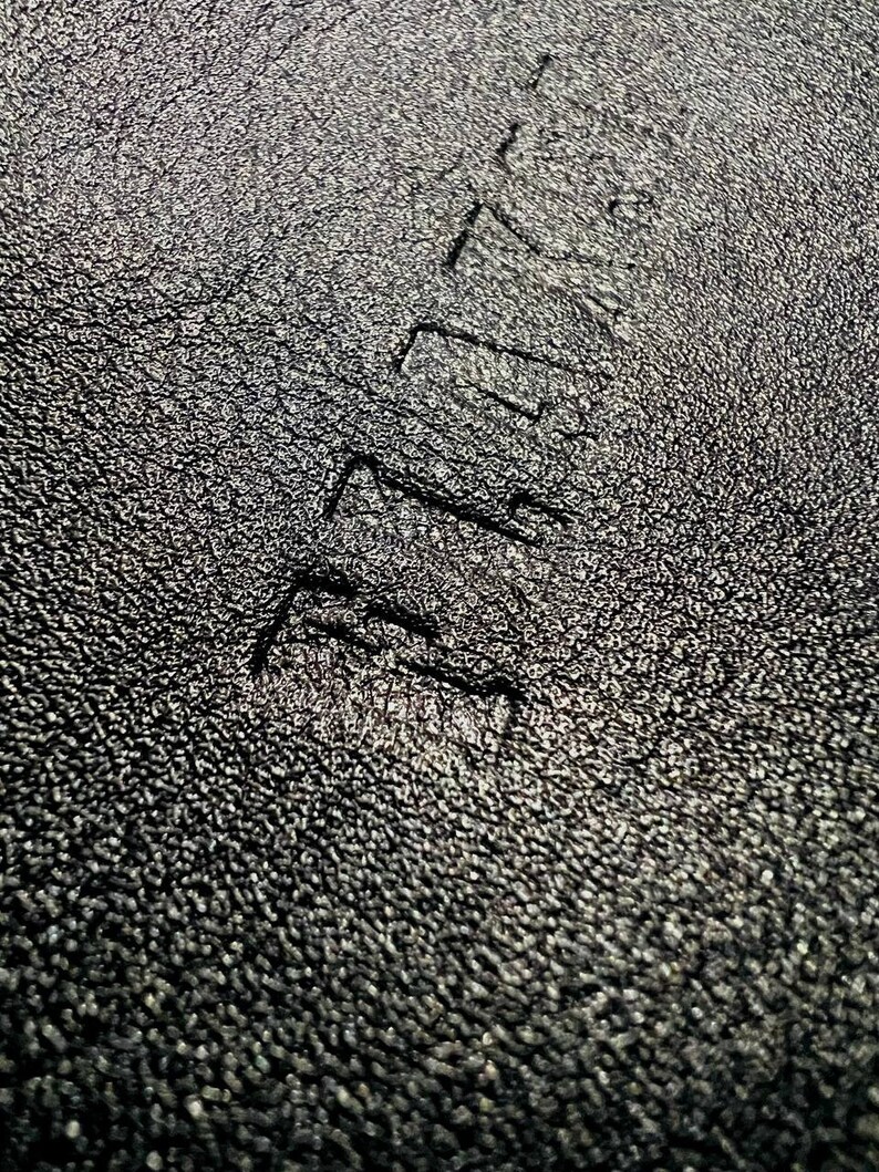 May include: Close-up of a black textured surface with the word "REMARKABLE" embossed in white.