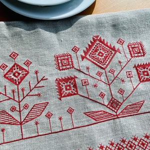 Linen table runner with red embroidered floral pattern