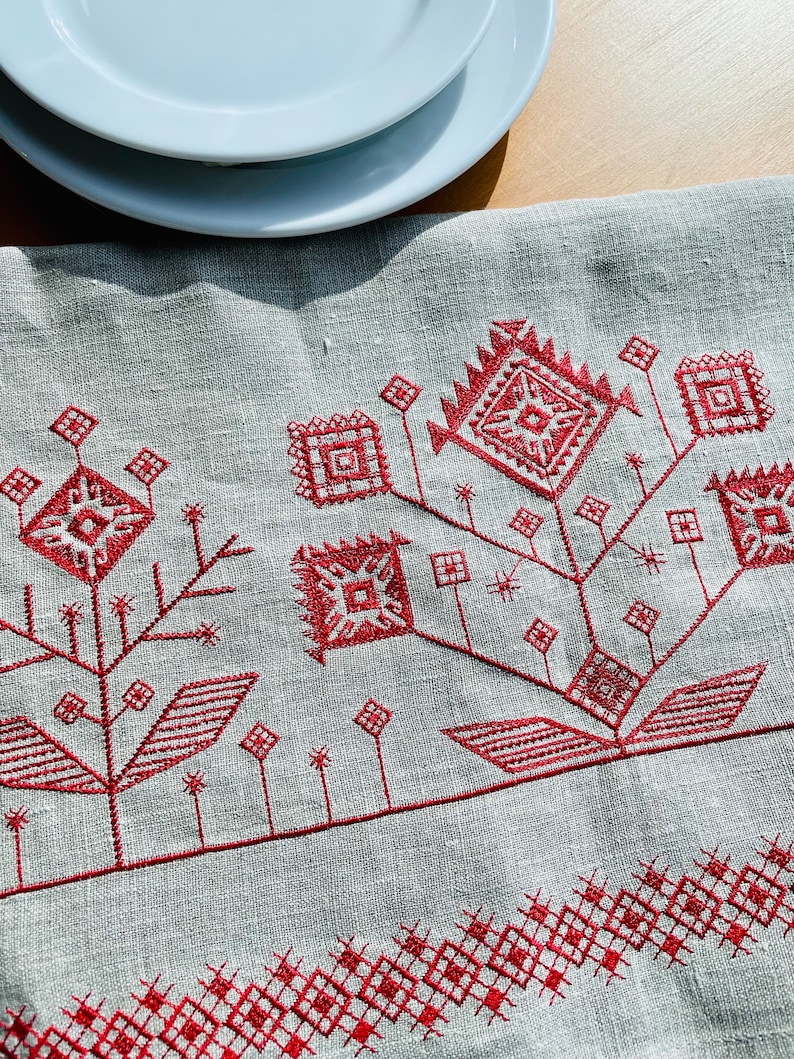 Linen table runner with red embroidered floral pattern