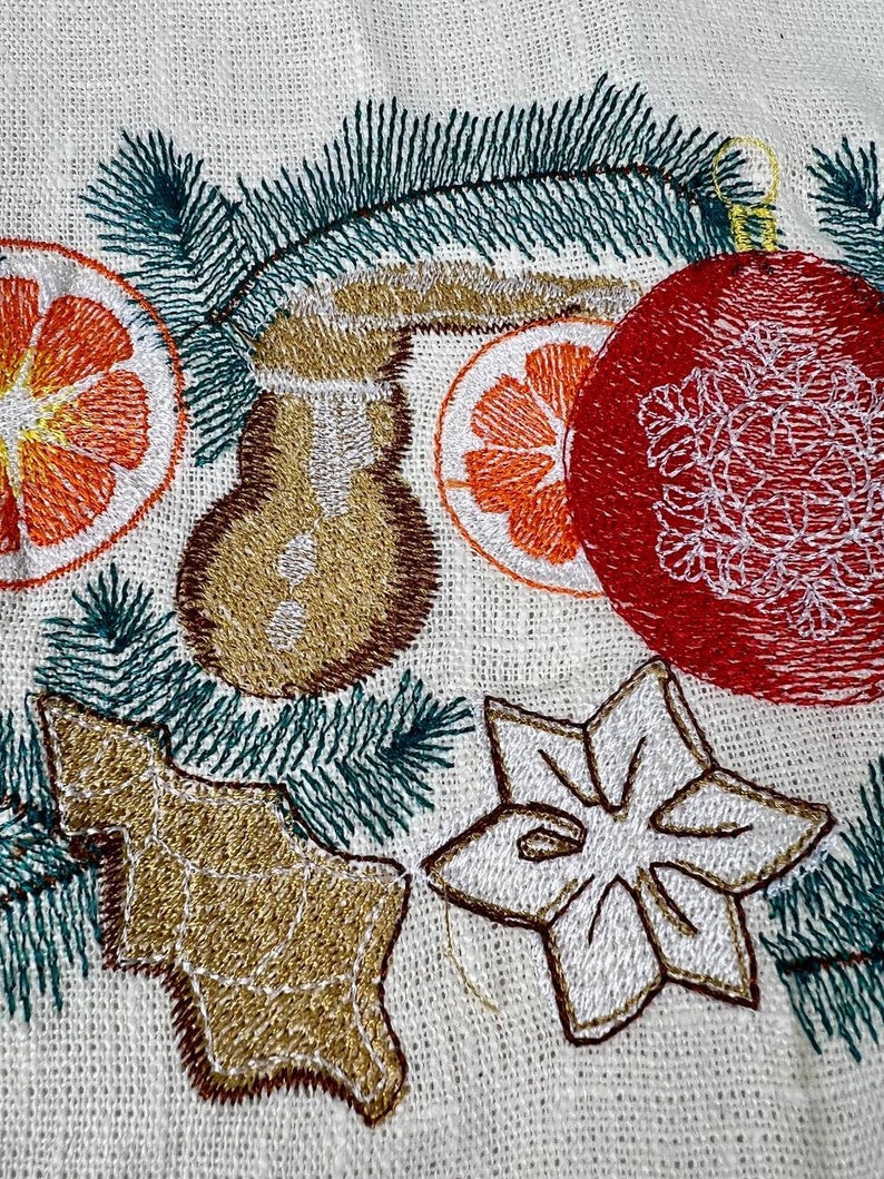 May include: Embroidered Christmas-themed design on a cream-colored fabric. Features a red ornament, orange citrus slices, a gingerbread man, a star, and green pine needles. The embroidery is in shades of gold, brown, orange, and white.