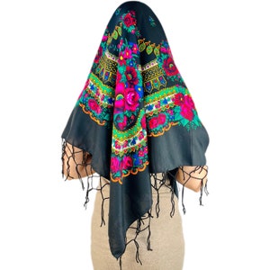 Pu&ograve; includere: Un foulard nero con un motivo floreale colorato e frange. Il motivo presenta fiori rossi, rosa, verdi, blu e gialli.