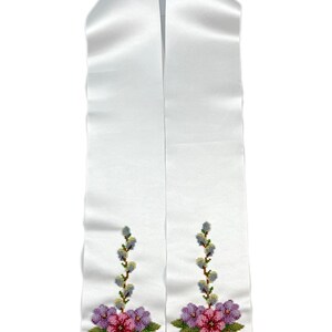 K&ouml;nnte beinhalten: Wei&szlig;e Satin-Abschlussband mit gestickten Blumendesigns in Rosa-, Lila- und Gr&uuml;nt&ouml;nen. Die Blumen sind von Weidenzweigen mit gr&uuml;nen Bl&auml;ttern und gelben Knospen umgeben.