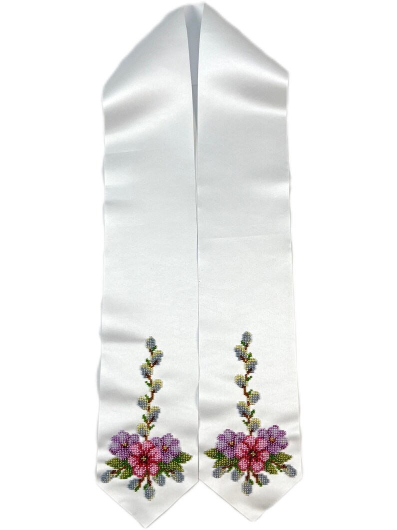 K&ouml;nnte beinhalten: Wei&szlig;e Satin-Abschlussband mit gestickten Blumendesigns in Rosa-, Lila- und Gr&uuml;nt&ouml;nen. Die Blumen sind von Weidenzweigen mit gr&uuml;nen Bl&auml;ttern und gelben Knospen umgeben.