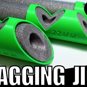 May include: Green 3D-printed lagging jigs with gray foam inserts, designed to hold insulation around pipes. The jigs are labeled with sizes like 22MM and 28MM. The text "LAGGING JIG" is displayed in large white letters.