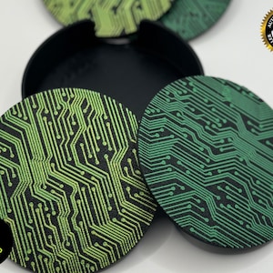 Op de afbeelding: Set van vier ronde onderzetters met een groen en zwart printpatroon van een printplaat. De onderzetters hebben een verhoogde rand en zijn gemaakt van een duurzaam materiaal. Ze zijn perfect om uw meubels te beschermen tegen vlekken en krassen.