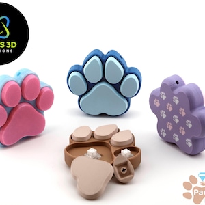 May include: Four different paw print shaped silicone toys in blue, pink, purple and brown. The blue and pink paw prints are solid, the purple paw print has a pattern of smaller paw prints, and the brown paw print is a puzzle with three pieces.
