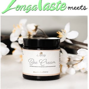 May include: A jar of "Bee Cream" with a black lid and a white label, set against a backdrop of white flowers. The label includes the text "Longa Taste meets" and "Bee Cream" with additional text in German.