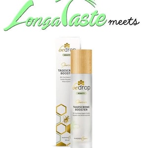 May include: A 50 ml bottle of bedrop beauty skincare day cream booster with a wooden cap. The bottle is white with gold lettering and a bee illustration. The text on the bottle reads "Shincare Tagescreme Booster Mit hochwertigen Gelee Royale und Niacinamide"