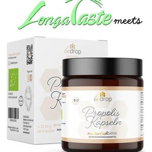May include: A brown jar with a white label that reads "Propolis Kapseln #natürlichbiene NAHRUNGSERGÄNZUNGSMITTEL" and a smaller label that reads "bedrop". The jar is sitting on a white box with a green logo and the text "Longa taste meets".
