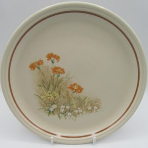 May include: A white ceramic dinner plate with a brown rim and a floral design featuring orange and yellow flowers on a beige background.