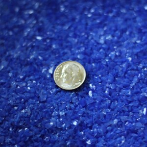 May include: A close-up of a US coin on a bed of blue glass beads.