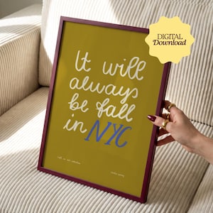 Könnte beinhalten: Ein gerahmter Kunstdruck mit senfgelbem Hintergrund und dunkelrotem Rahmen. Der Text "It will always be fall in NYC" ist in weißer und blauer Schreibschrift zu sehen. Ein gelbes sternförmiges Abzeichen trägt die Aufschrift "DIGITAL Download".
