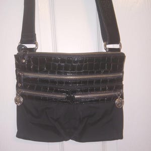 May include: A white ceramic mug with a black handle and the text "But First, Coffee" in a bold, black font. The mug is filled with a dark liquid, likely coffee, and sits on a light-colored surface.