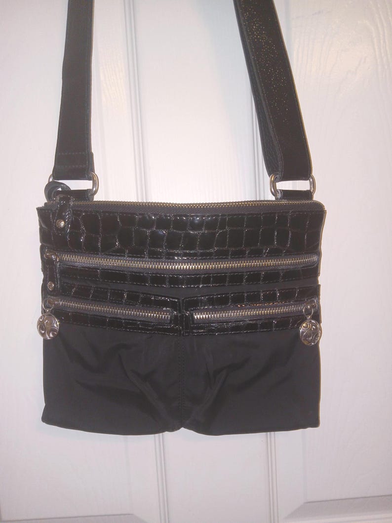 May include: A white ceramic mug with a black handle and the text "But First, Coffee" in a bold, black font. The mug is filled with a dark liquid, likely coffee, and sits on a light-colored surface.