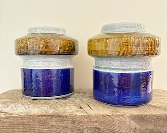 May include: Two ceramic vases with a blue, white and brown glaze. The vases have a wide, rounded base and a narrow neck.