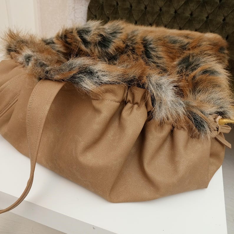 Pu&ograve; includere: Una borsa a cordoncino in similpelle marrone con un bordo in pelliccia sintetica a stampa leopardata.