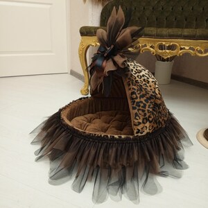 May include: A brown and black leopard print dog bed with a brown tulle skirt and a brown and black bow on top.