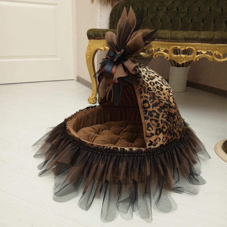 May include: A brown and black leopard print dog bed with a brown tulle skirt and a brown and black bow on top.