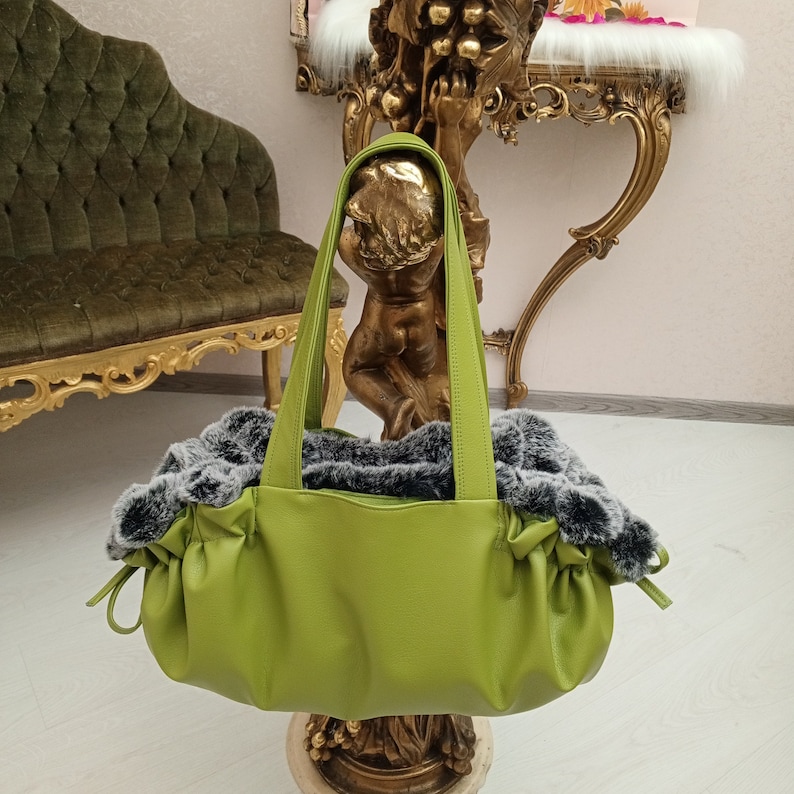 May include: A lime green faux leather pet carrier with a grey faux fur lining. The carrier has two handles and a gathered design.