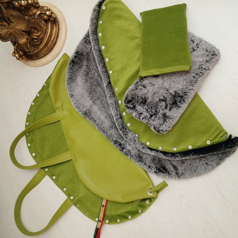 May include: A green faux fur lined tote bag with a large, rounded bottom and a top handle. The bag has silver studs around the edge and a decorative strap.