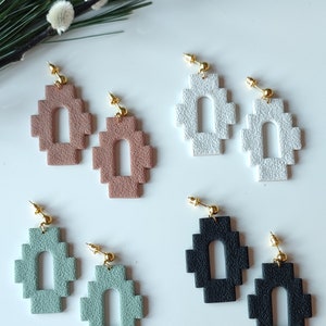 Op de afbeelding: Een set van zes paar geometrische boog oorringen in verschillende kleuren, waaronder zwart, wit, saliegroen en bruin. De oorringen zijn gemaakt van een getextureerd materiaal en hebben een modern, minimalistisch ontwerp.
