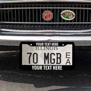 May include: A dark green classic convertible car, viewed from the front. Features include chrome bumpers, round headlights, and a license plate displaying "70 MGB". The car is parked outside on a sunny day.