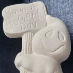 May include: White ceramic ghost holding a sign that says "Have a Boo-tiful Day".
