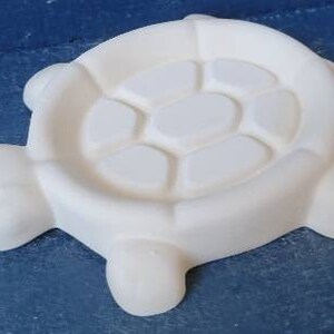 May include: White ceramic turtle shaped dish with a raised shell design. The dish is perfect for holding small items like jewelry or keys.