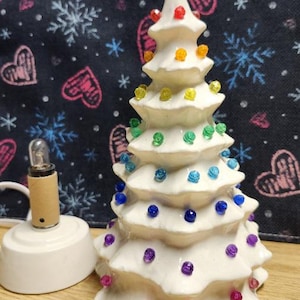 Glazed white tree and base 9 &quot; tall. Minimalist tree with multi-color bulbs. Ceramic Christmas Tree lights up. Priced per tree, 2 shown.