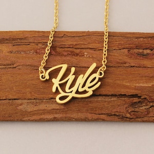 May include: Gold necklace with the name "Kyle" written in a cursive script.