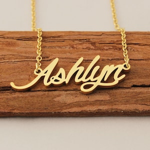 Könnte beinhalten: Eine goldene Halskette mit dem Namen "Ashlyn" in Schreibschrift.