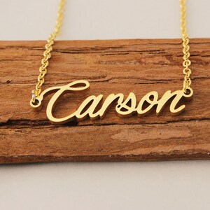 May include: Gold necklace with the name "Carson" written in a cursive script.