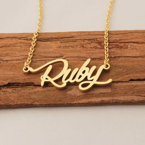 Könnte beinhalten: Goldkette mit dem Namen "Ruby" in Schreibschrift.