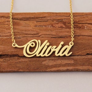 May include: Gold necklace with the name "Olivia" spelled out in a cursive font.