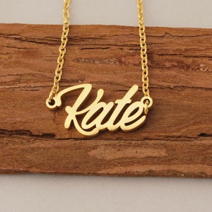Könnte beinhalten: Goldkette mit dem Namen "Kate" in kursivschrift.