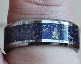 Könnte beinhalten: Ein silberner Ring mit einer blauen und goldenen Einlage. Der Ring hat eine abgeschrägte Kante und eine polierte Oberfläche.