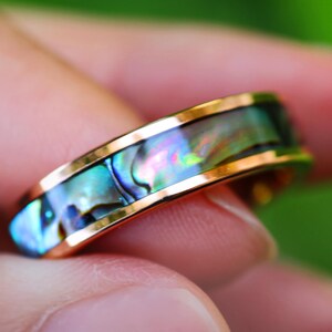 Könnte beinhalten: Ein Goldring mit einer blauen, grünen und schillernden Abalone-Muscheleinlage.