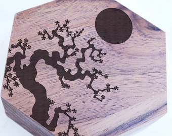 May include: A hexagonal wooden coaster with a laser-etched design of a tree with a circle in the upper right corner.