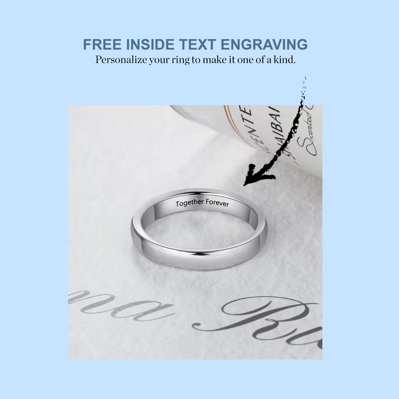 May include: A silver wedding band with the inscription "Together Forever" engraved on the inside. The ring is lying on a white surface.